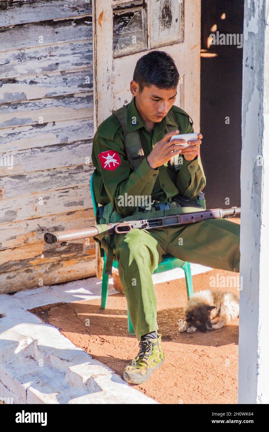 PWE KAUK, MYANMAR - 30. NOVEMBER 2016: Wachsoldat am Bahnhof Pwe Kauk Pwekawk konzentriert sich auf sein Smartphone Myanmar Stockfoto
