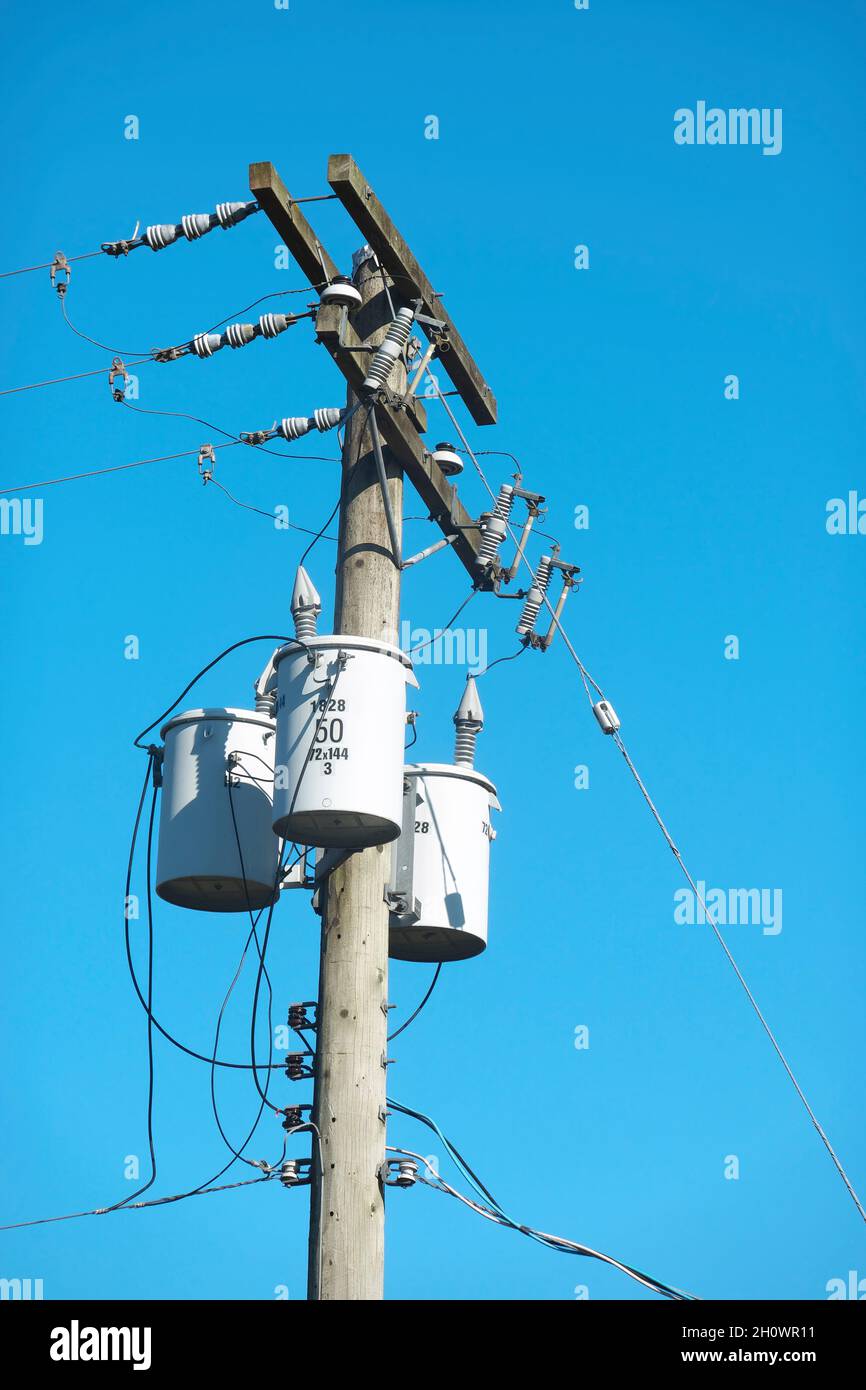Transformatoren und Stromleitungen vor blauem Himmel. Stockfoto