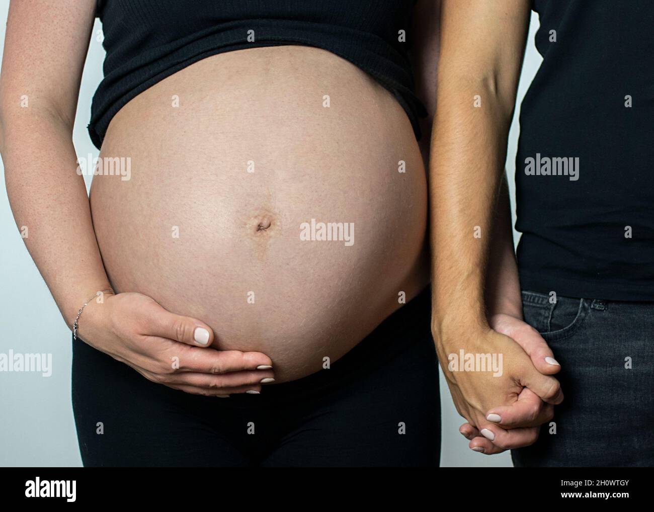 Der Bauch der zukünftigen Mutter und ein unterstützender zukünftiger Vater. Stockfoto