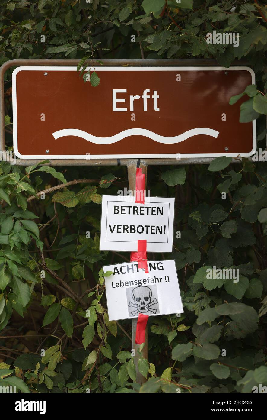 Erftstadt, Deutschland. Oktober 2021. Ein Schild hinter einem Sperrband auf einer Brücke weist auf den Fluss Erft im Bezirk Blessem, darunter weitere Schilder mit den Aufschrift „nicht betreten“ und „Vorsicht, Lebensgefahr“. In Blessem öffnete sich die Erde in der Nacht des 15. Juli und verschlang mehrere Häuser. (To dpa: ''You take that to the Grave' - Ein Viertel Jahr nach der Flut') Quelle: Oliver Berg/dpa/Alamy Live News Stockfoto