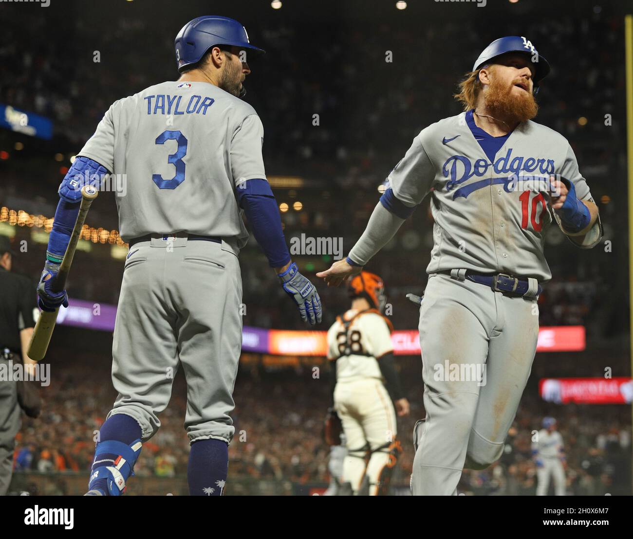San Francisco, USA. Oktober 2021. Los Angeles Dodgers Justin Turner, rechts, punktet im Spiel 5 der National League Division Series im Oracle Park am Donnerstag, den 14. Oktober 2021 in San Francisco den Siegerlauf gegen die San Francisco Giants. Die Dodgers besiegten die Giants 2-1 und gewannen die National League Division Series. Dodgers Chris Taylor (3) ist links, und Giants Buster Posey ist hinten in der Mitte. Foto von George Nikitin/UPI Credit: UPI/Alamy Live News Stockfoto