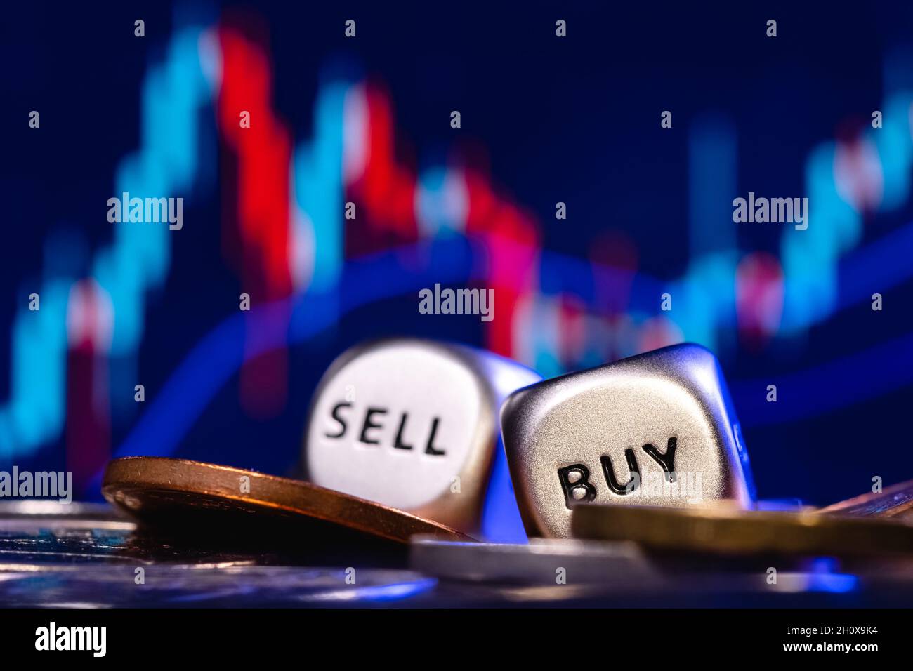 Ein zwei Metalldices in einem Stapel von Münzen auf dem Hintergrund der Aktienkarte. Das Konzept der Buy-Sell-Wahl. Stockfoto