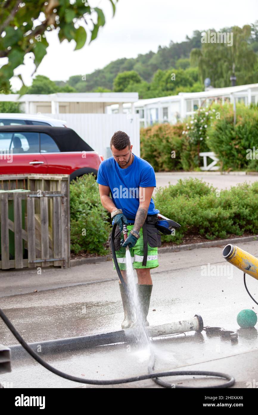 Mann benutzt Schlauchleitung auf der Baustelle Stockfoto