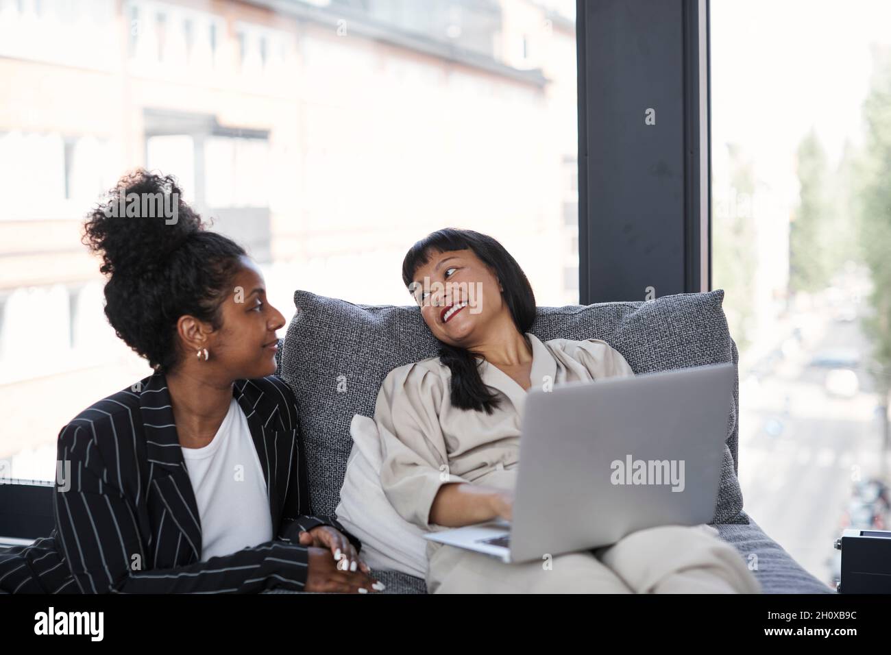 Lächelnde weibliche Kollegen sitzen zusammen Stockfoto