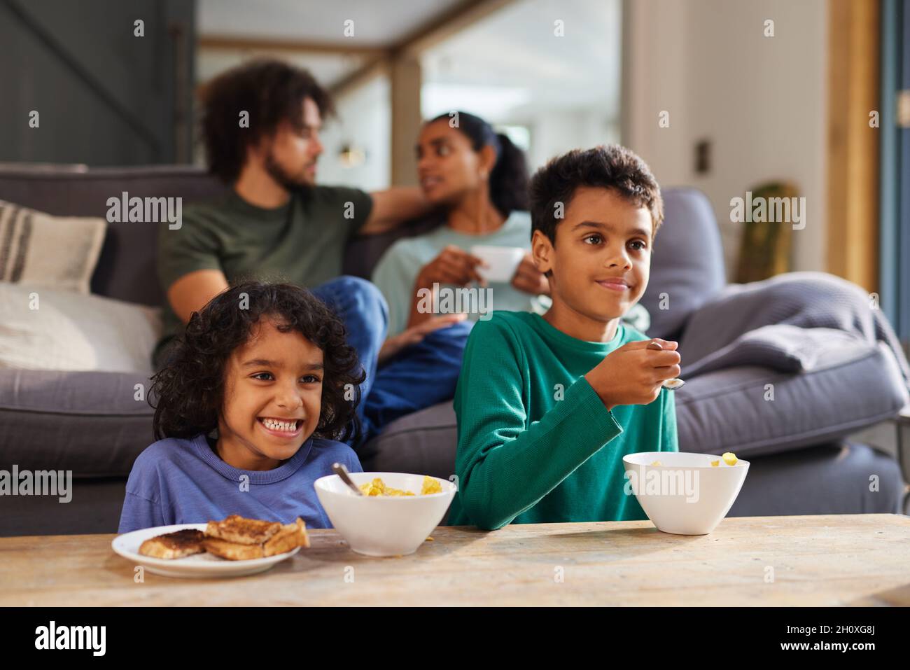 Kinder sehen fern und frühstücken mit ihren Eltern Stockfoto