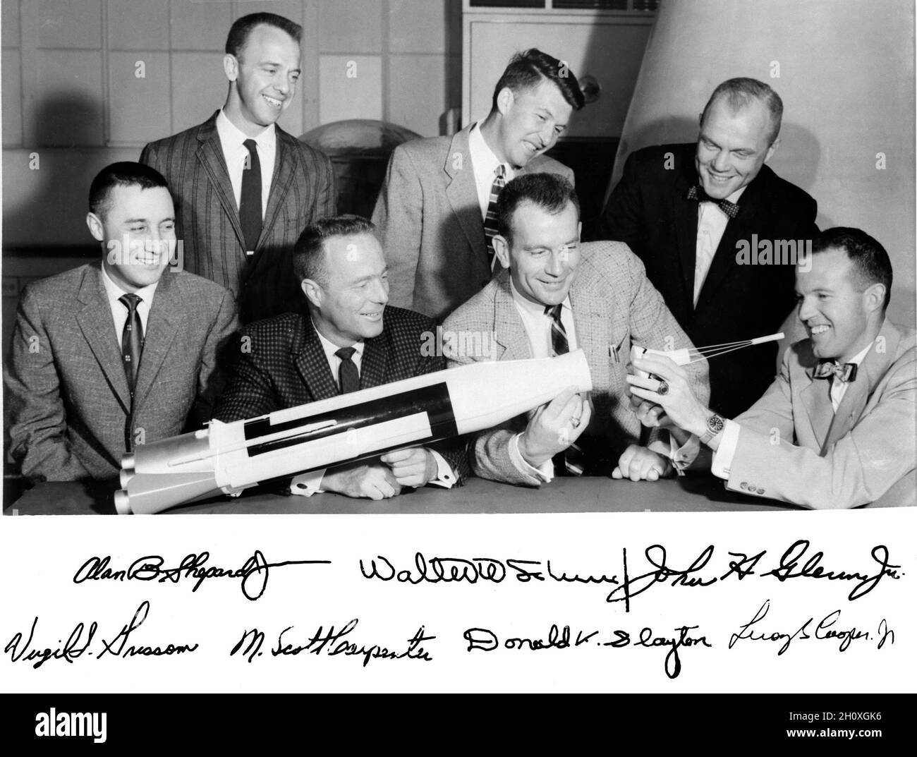 (1959) --- die ursprünglichen Merkur-Astronauten sind um einen Tisch herum abgebildet und bewundern ein Atlas-Modell. Stehend, von links nach rechts, sind Alan B. Shepard Jr., Walter M. Schirra Jr. und John H. Glenn Jr.; sitzend, von links nach rechts Virgil I. Grissom, M. Scott Karpenter, Donald Slayton und L. Gordon Cooper Jr. Stockfoto