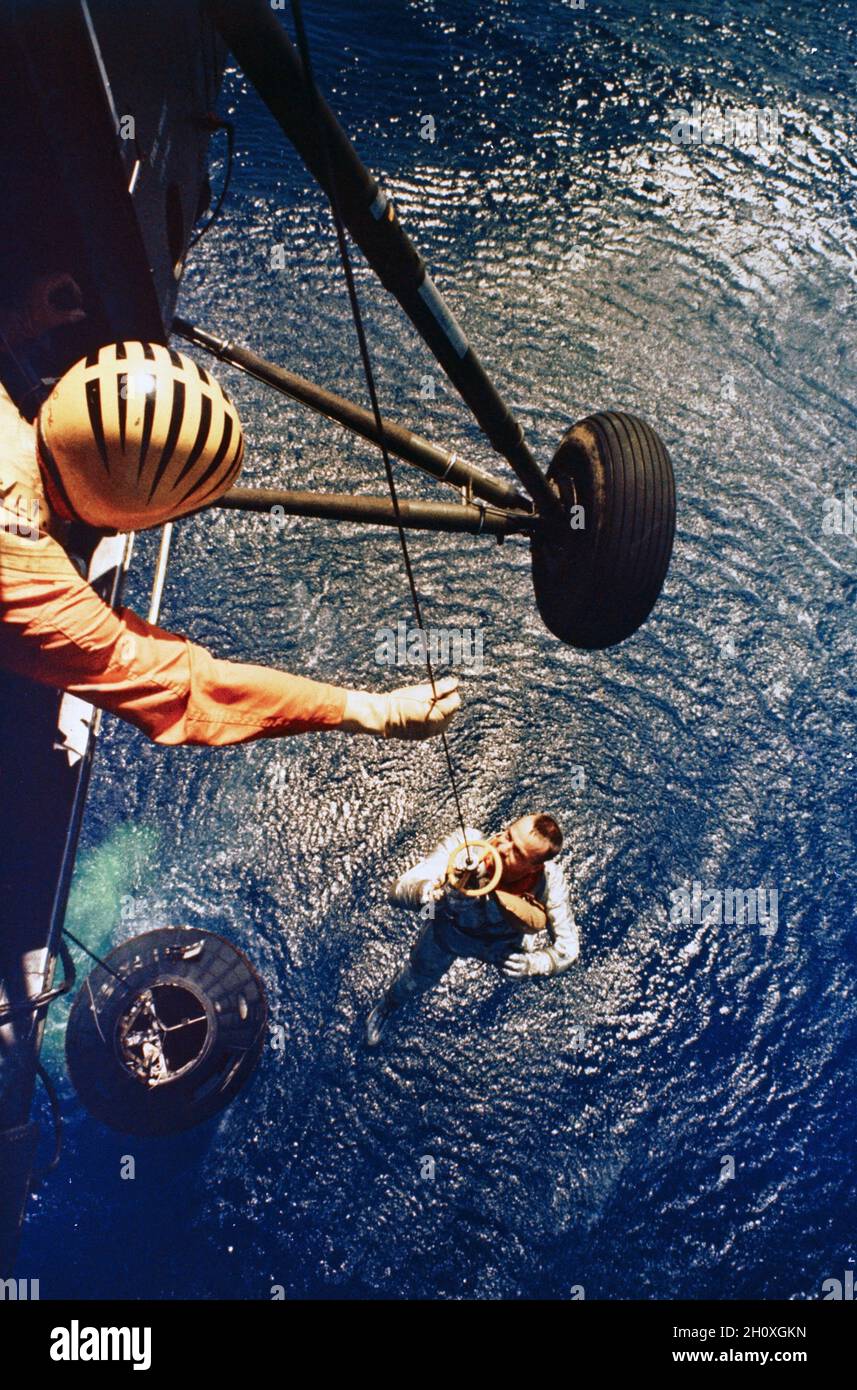 (5. Mai 1961) --- Astronaut Alan B. Shepard Jr., Pilot des Suborbitalen Weltraumfluges Mercury-Redstone 3 (MR-3), wird von einem Hubschrauber aus der USS Lake Champlain während der Bergeoperationen im westlichen Atlantischen Ozean abgeholt. Shepard und die Mercury-Raumsonde, die die 'Freedom 7' (schwimmend im Wasser unten) bezeichnete, wurden innerhalb von 11 Minuten nach dem Spritzwassereinlauf zum Deck des Bergeschiffes geflogen. MR-3 war die erste bemannte Weltraummission der Vereinigten Staaten. Die Raumsonde erreichte eine Höchstgeschwindigkeit von 5,180 Meilen pro Stunde, erreichte eine Höhe von 116 1/2 Meilen und landete 302 Meilen in der Tiefe Stockfoto