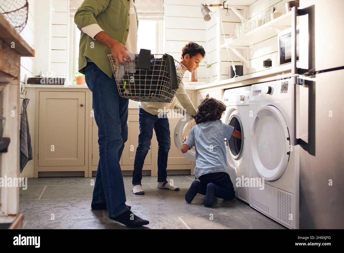 Jungen, die Wäsche waschen, während Vater den Korb hält Stockfoto