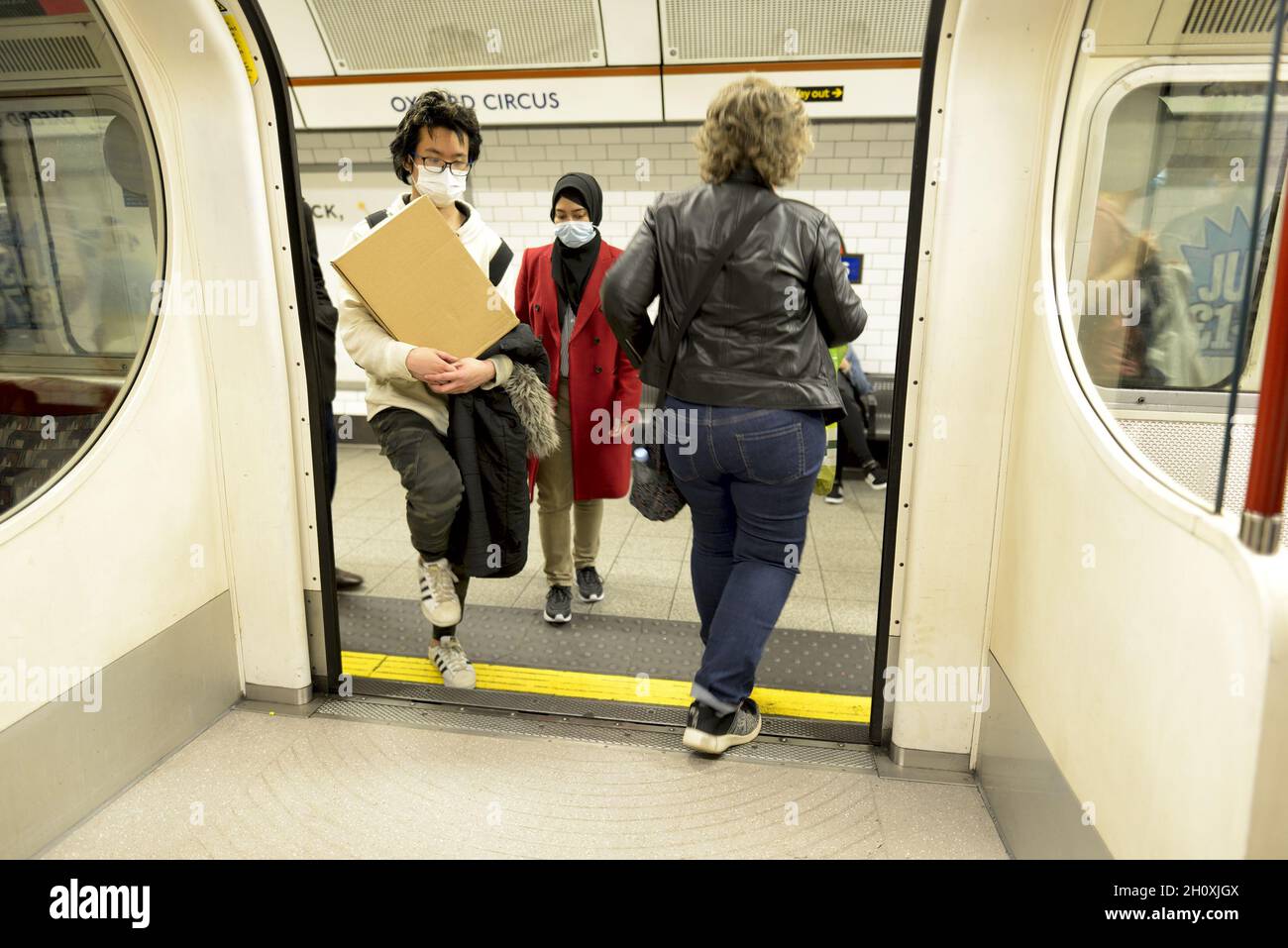 London, England, Großbritannien. U-Bahn in London: Menschen in COVID maskiert das Einsteigen in einen Zug am Oxford Circus Stockfoto