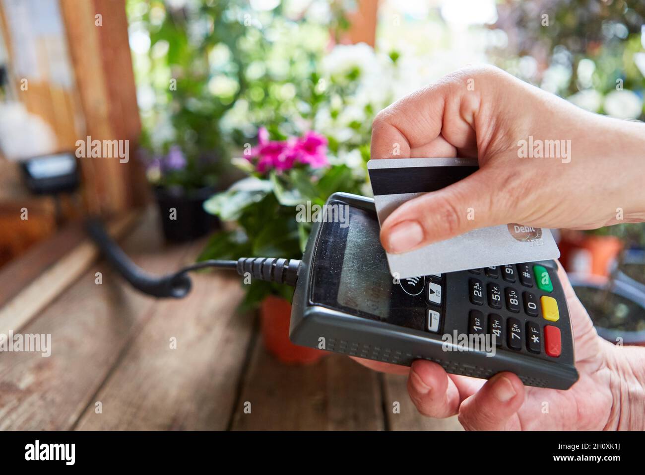 Kunde bei Zahlung an der Gartenkasse mit Kreditkarte oder Kundenkarte Stockfoto