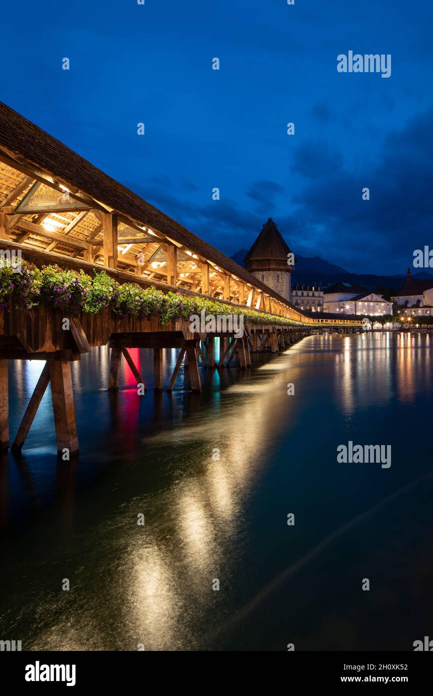 Kapellbrücke, mittelalterliche Brücke in Luzern bei Nacht. Die Brücke ist beleuchtet, die Lichter werden im See reflektiert. Beeindruckende Aussicht auf die Stadt Stockfoto