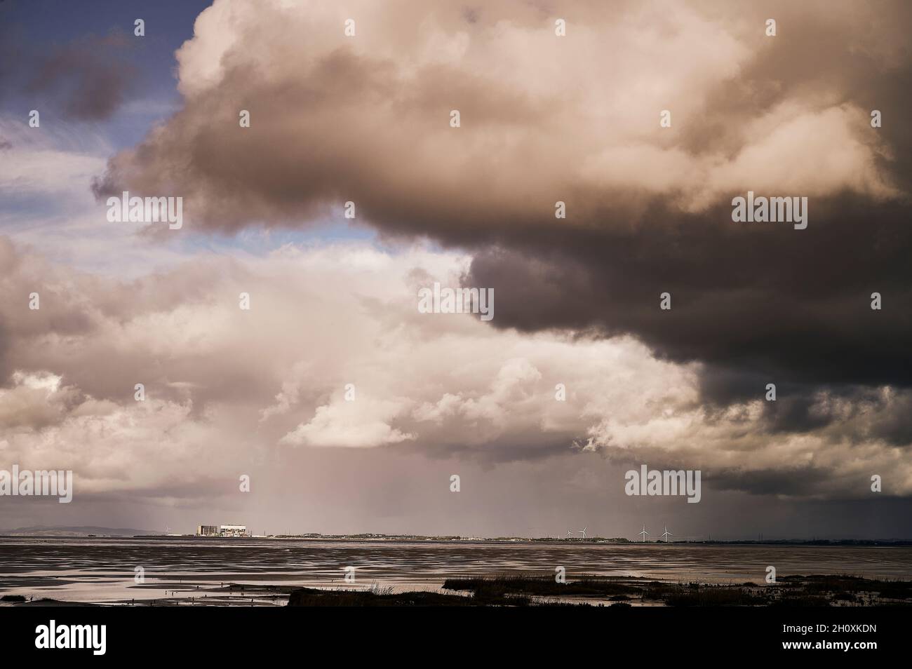 Kernkraftwerk und Windpark unter stürmischem Himmel Stockfoto