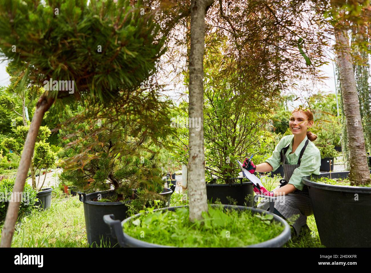 Junge Gärtnerin mit Checkliste in Baumschule mit Klimawandel Bäumen Stockfoto