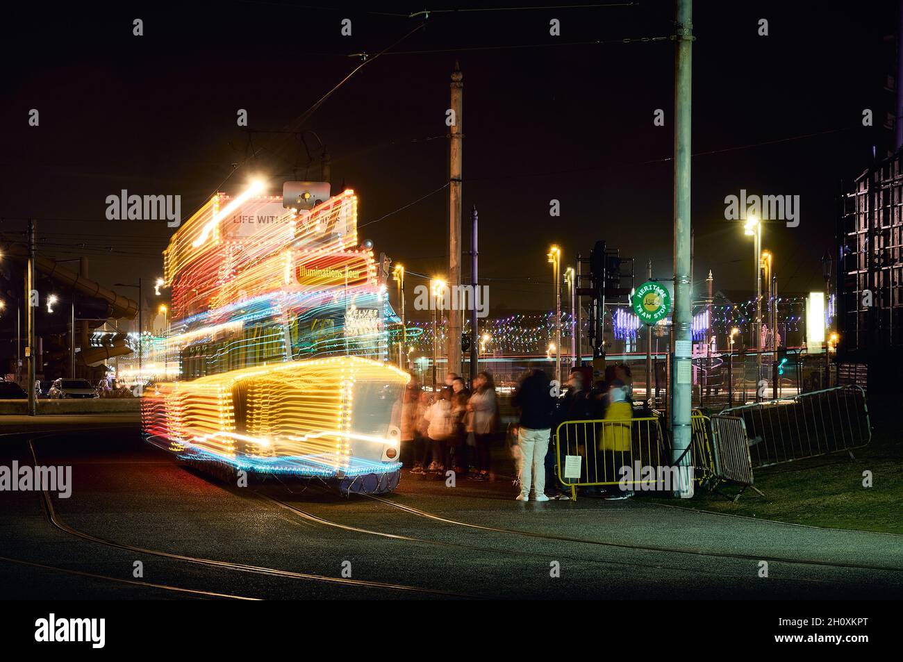 Schlange von Menschen, die auf die Ankunft einer beleuchteten Straßenbahn warten, um die Lichter von Blackpool zu besichtigen Stockfoto