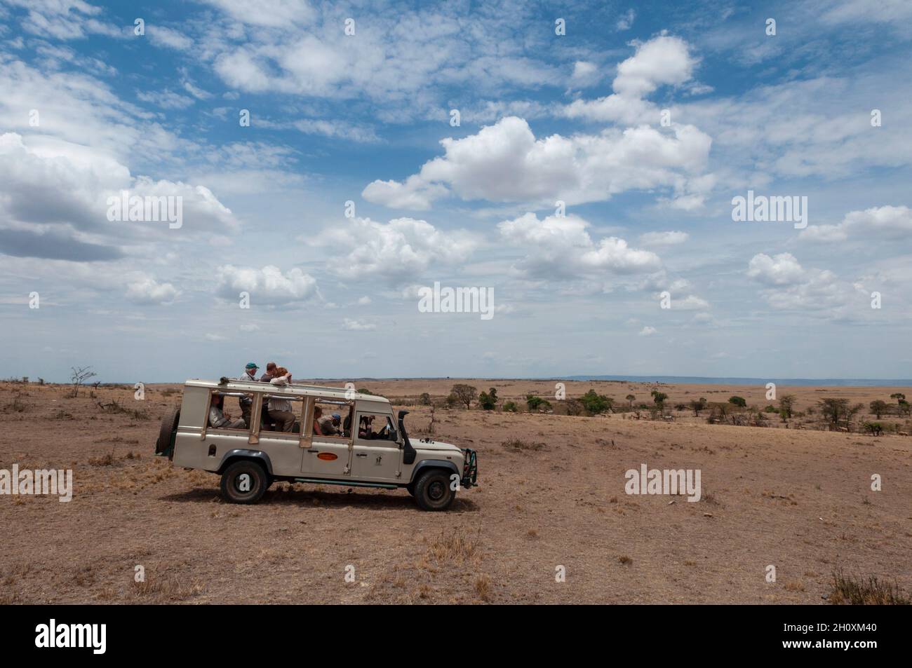 Ein Safari-Fahrzeug voller Touristen in den weiten Ebenen des Masai Mara National Reserve. Masai Mara National Reserve, Kenia. Stockfoto