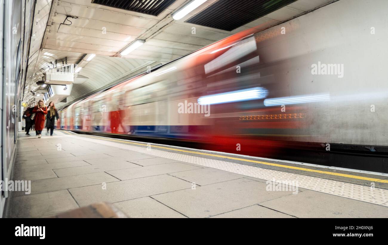 U-Bahn London. Lange Belichtungszeit, Weitwinkelunschärfe einer U-Bahn, die die Plattform eines Bahnhofs verlässt und Passagiere in die Nacht gebracht haben Stockfoto