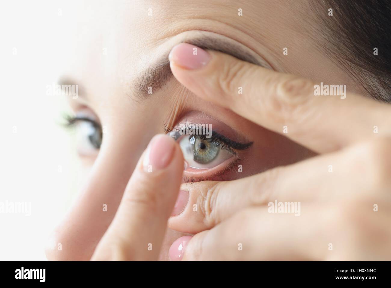 Frau zieht aus der Nähe weiche Kontaktlinsen an Stockfoto