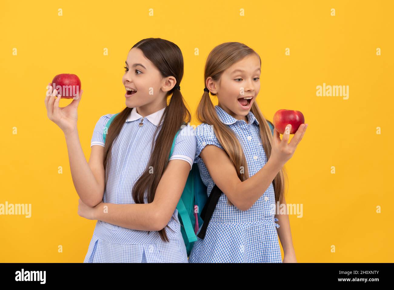 Gesundheit versteckt in Äpfeln. Überraschte Kinder schauen auf Äpfel gelben Hintergrund. Essen Sie mehr Obst Stockfoto