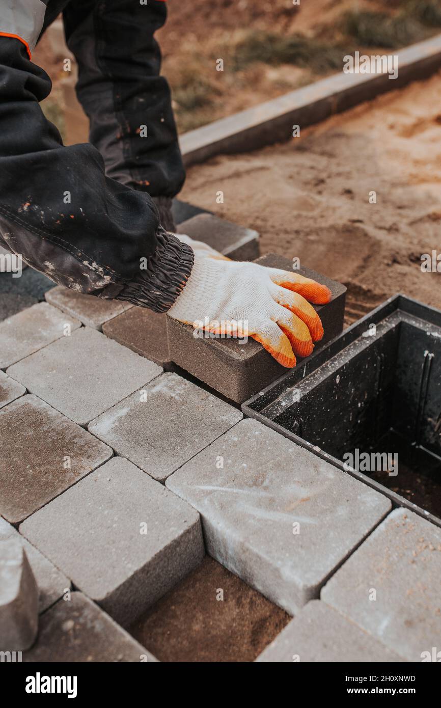 Die Technologie der Verlegung von Naturstein aus Pflasterplatten - die Arbeit eines Maurerlayers, um den Boden außerhalb zu installieren Stockfoto