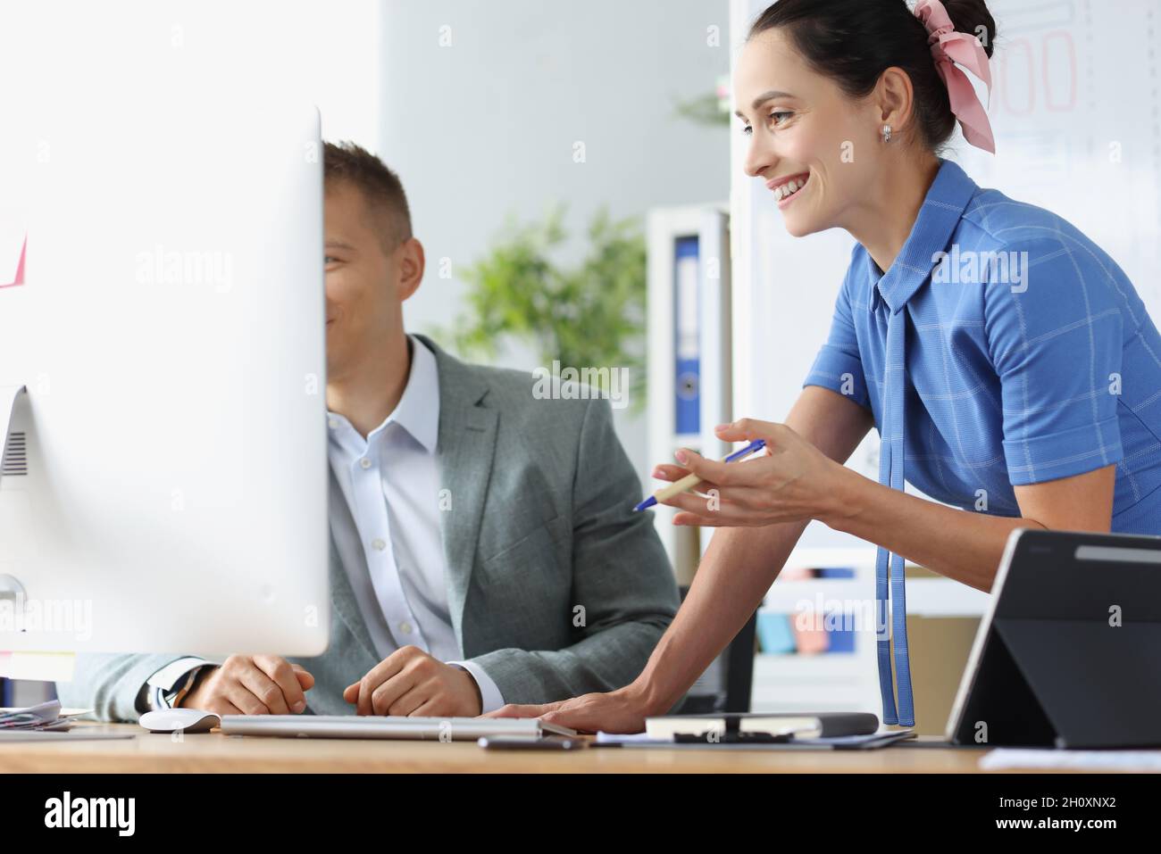 Lächelnder Mann und Frau diskutieren am Arbeitstisch über Geschäftsprozesse Stockfoto