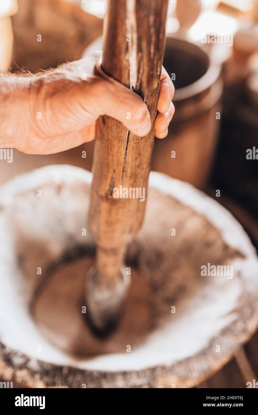 Ein Müllerbäcker mahlt mit der Hand in einem Holzmörtel mit alter Technik Stockfoto