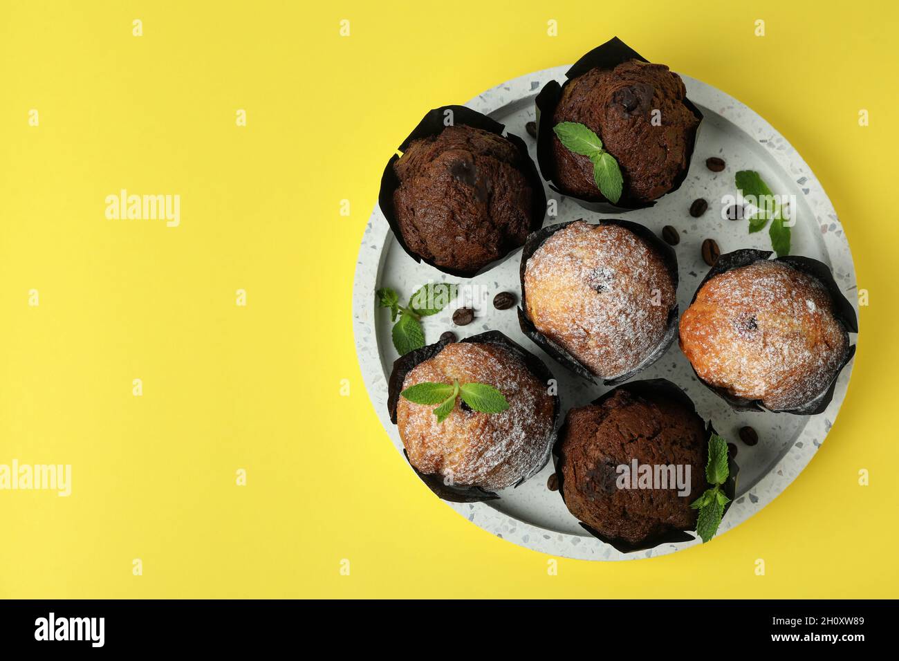 Tablett mit Schokoladen-Muffins auf gelbem Hintergrund. Stockfoto