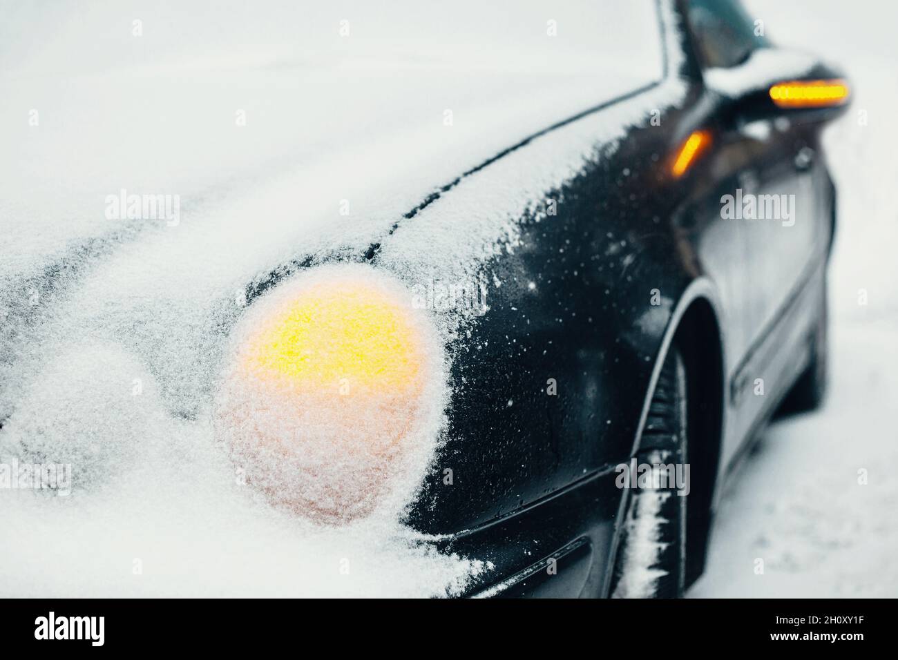 Auto unter Schnee mit Warnblinkanlage an - Not-aus bei frostigen Wetterbedingungen bei schwierigen Wetterbedingungen Stockfoto