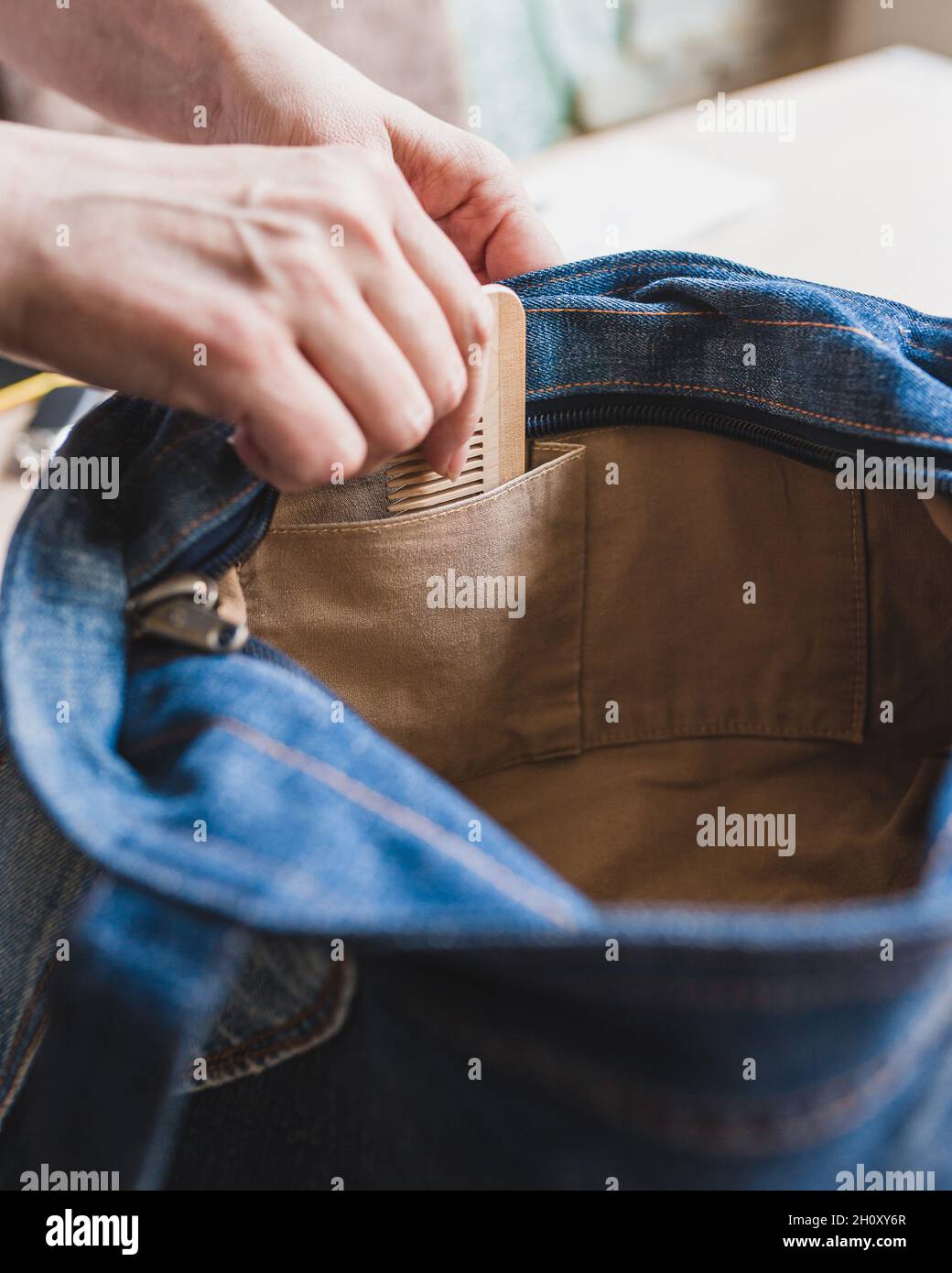 Eine nette, nette Frau steckt eine hölzerne Haarbürste in die Tasche ihrer Tasche - pflegen Sie ein gepflegtes Aussehen Stockfoto