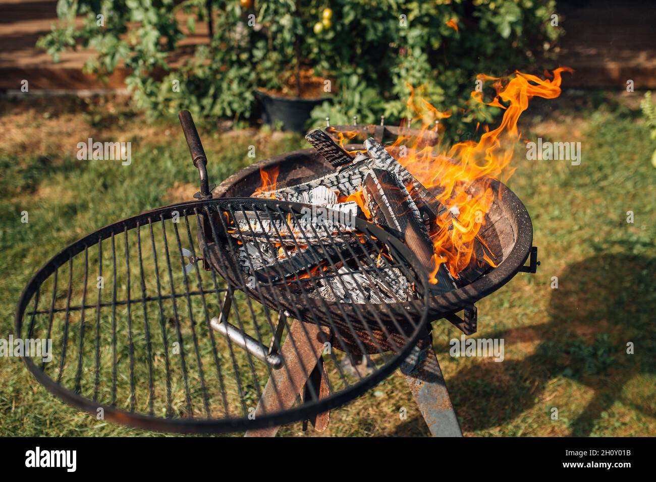 Rundes Grillrost aus Metall mit Feuer aus brennendem Holz Stockfotografie -  Alamy