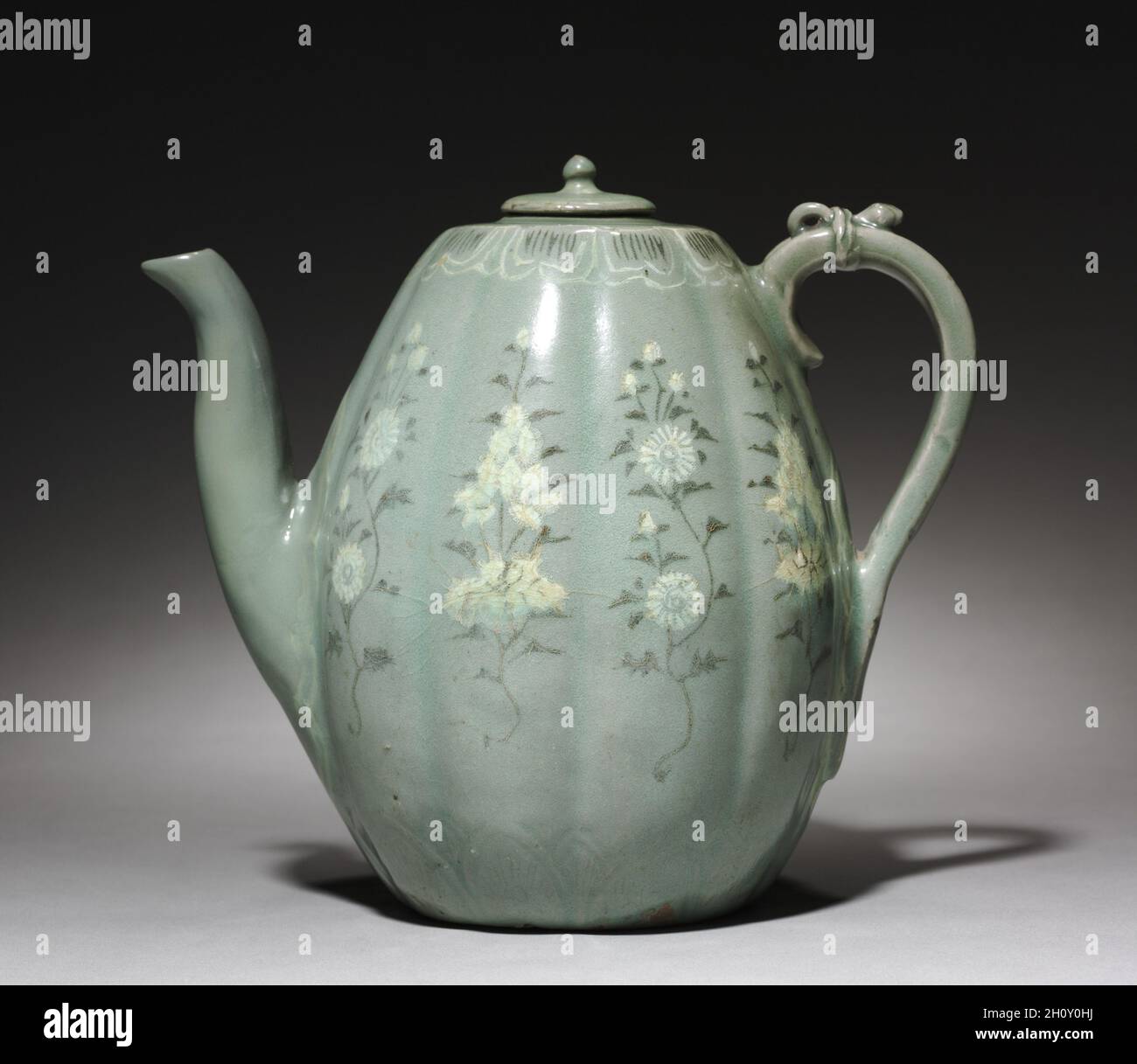 Krug mit eingelegter Chrysantheme und Peony Design, 1200er. Korea, Goryeo-Zeit (918-1392). Celadon-Ware mit eingelegter weißer und schwarzer Slip-Dekoration; Höhe mit Deckel: 20.6 cm (8 1/8 in.); Außendurchmesser: 15 cm (5 7/8 in.). Dieser melonenförmige Krug ist mit einer zarten Zeichnung geschmückt, die Chrysantheme-Knospen mit vollen Blüten in weißen und schwarzen Intarsien macht. In Korea wurden Chrysantheme-Blumen und -Blätter zu Tee und Wein hergestellt. Chrysantheme-Wein wurde während des Double Nine Festivals (dem neunten Tag des neunten Monats im Mondkalender) genossen, während dem die Menschen für longevi beten Stockfoto