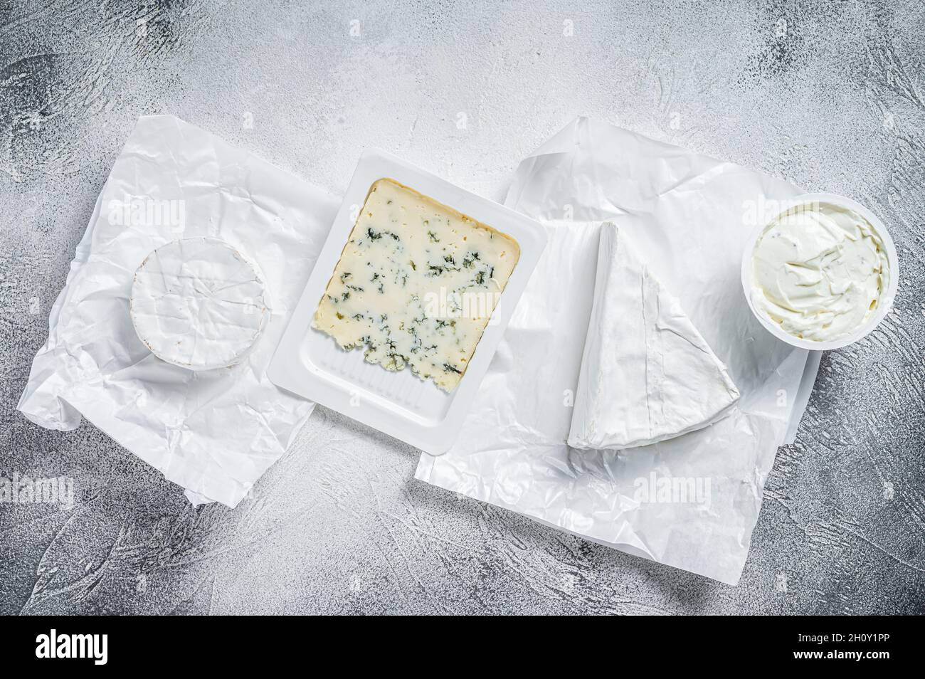Verschiedene Käsesorten auf Küchentisch, Brie, Camembert, Gorgonzola und blauer Cremekäse. Weißer Hintergrund. Draufsicht Stockfoto