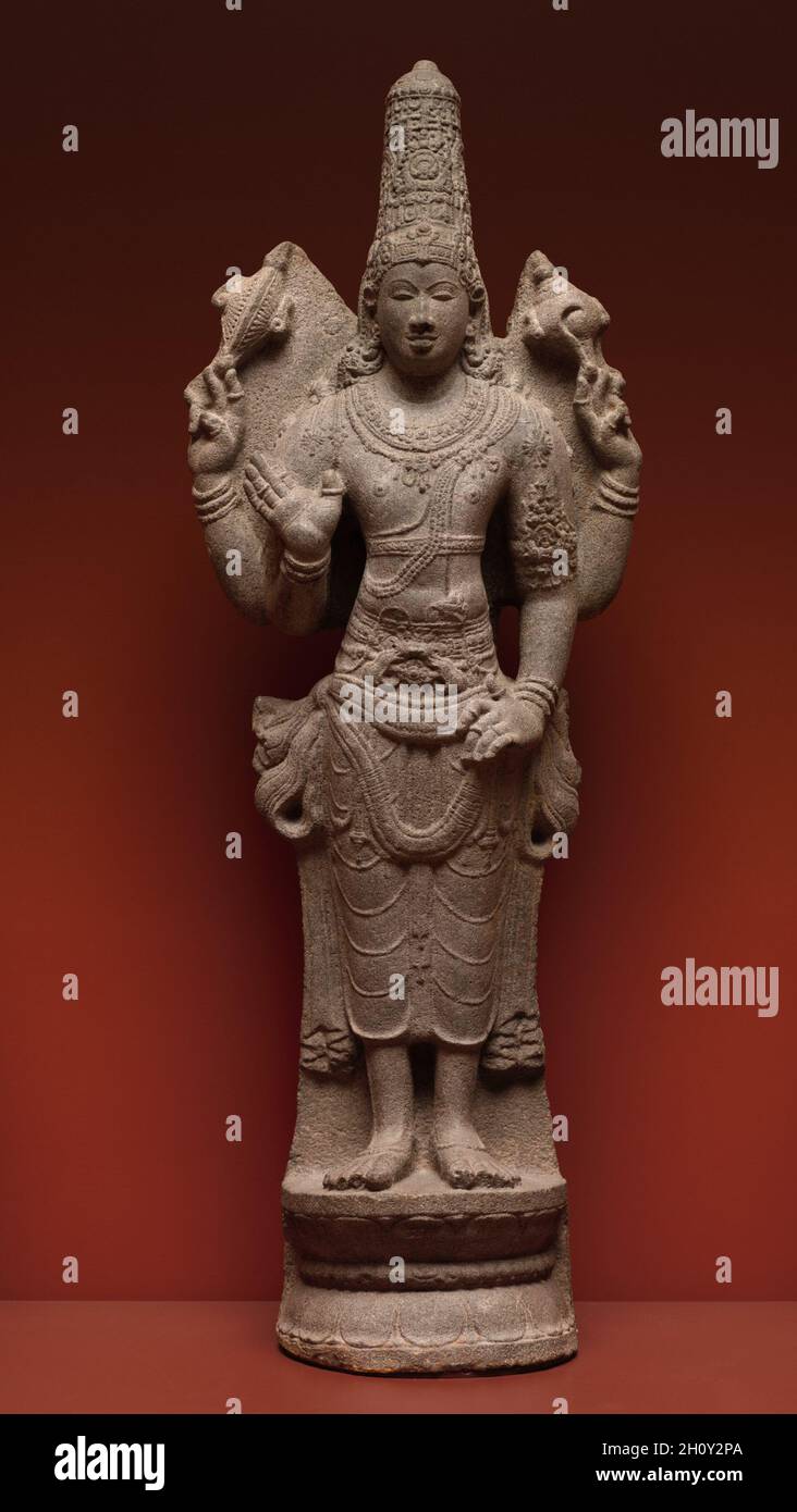 Vishnu, 900-950. Südindien, Tamil Nadu, wahrscheinlich Pudokkatai, frühe Chola-Dynastie, 10. Jahrhundert. Granit; insgesamt: 129.5 x 38.1 cm (51 x 15 Zoll). Vishnu wird hier in seiner Form als höchster herr gezeigt, seine hohe Krone weist auf seinen königlichen Aspekt hin; seine vier Arme offenbaren seine übermenschliche Natur. Seine obere rechte Hand hält einen Diskus, von der Seite gesehen. In seiner linken oberen Hand hält er die Muschelschale. Stockfoto