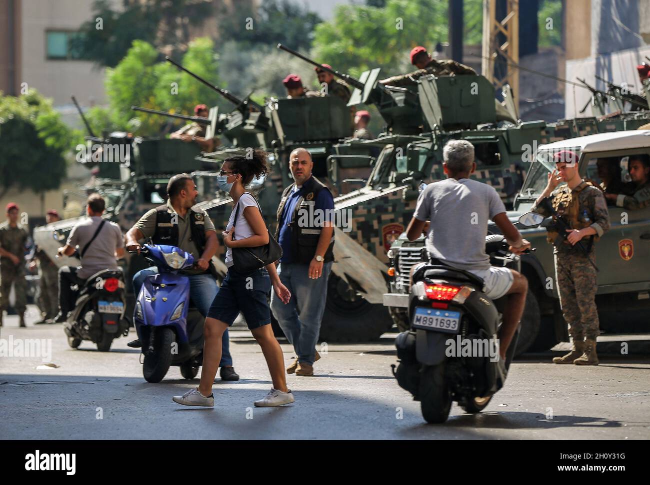 Beirut, Libanon. Oktober 2021. Eine Libanesin überquert die Straße im christlichen Gebiet von Ain al-Remaneh vor den gepanzerten Personentransportern (APC) der libanesischen Armeekommandos, die den Bezirk sichern, nach den tödlichen gewalttätigen Zusammenstößen zwischen muslimischen schiitischen Militanten der pro-iranischen Hisbollah und Gegnern von gestern. Bei einem Protest gegen einen Richter, der die massive Explosion im Hafen der Stadt im vergangenen Jahr untersucht, wurden heute in Beirut mindestens sechs Menschen getötet und 32 weitere verletzt. Quelle: Marwan Naamani/dpa/Alamy Live News Stockfoto