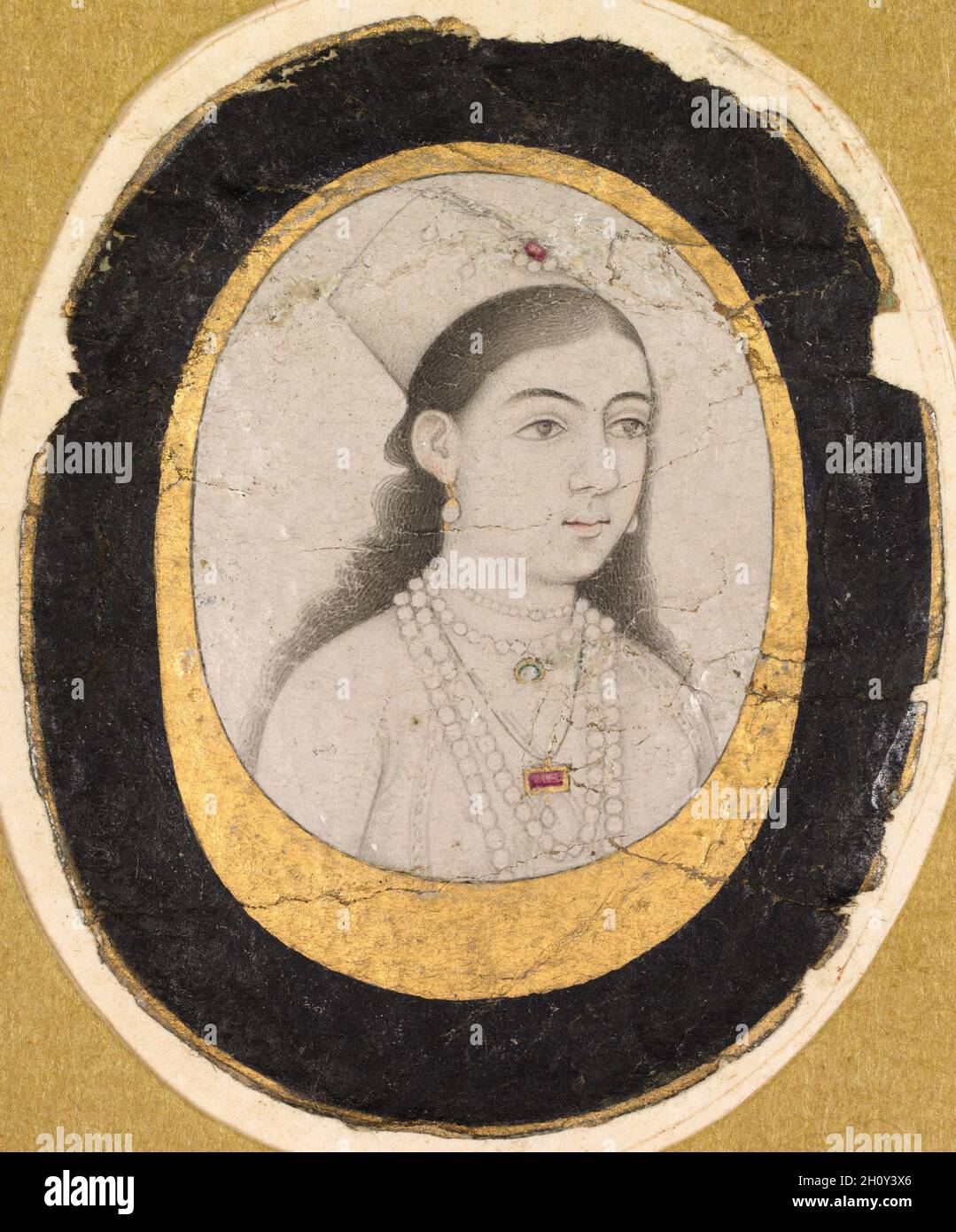 Juwel Porträt eines jungen Mädchen, c.. 1660. Indien, Mughal, 17. Jahrhundert. Tuschezeichnung mit leichten Farbakzenten; Bild: 3.3 x 2.4 cm (1 5/16 x 15/16 Zoll); insgesamt: 4.6 x 3.8 cm (1 13/16 x 1 1/2 Zoll). Diese kleine Zeichnung eines jungen Mädchens, das eine Chaghtai-Mütze trägt, kann ein Abbild eines Mitglieds einer königlichen oder höfischen Mughal-Familie sein. Die Genauigkeit der weiblichen Porträtaufnahmen ist ein ungelöstes Problem in der Mogulkunst, da es viele Bilder von Frauen gibt, die eher Studien der weiblichen Schönheit als visuelle Aufzeichnungen von echten Menschen zu sein scheinen. Da das Mädchen in diesem Bild jedoch kein idealisierter Typ ist, ist es mehr Stockfoto