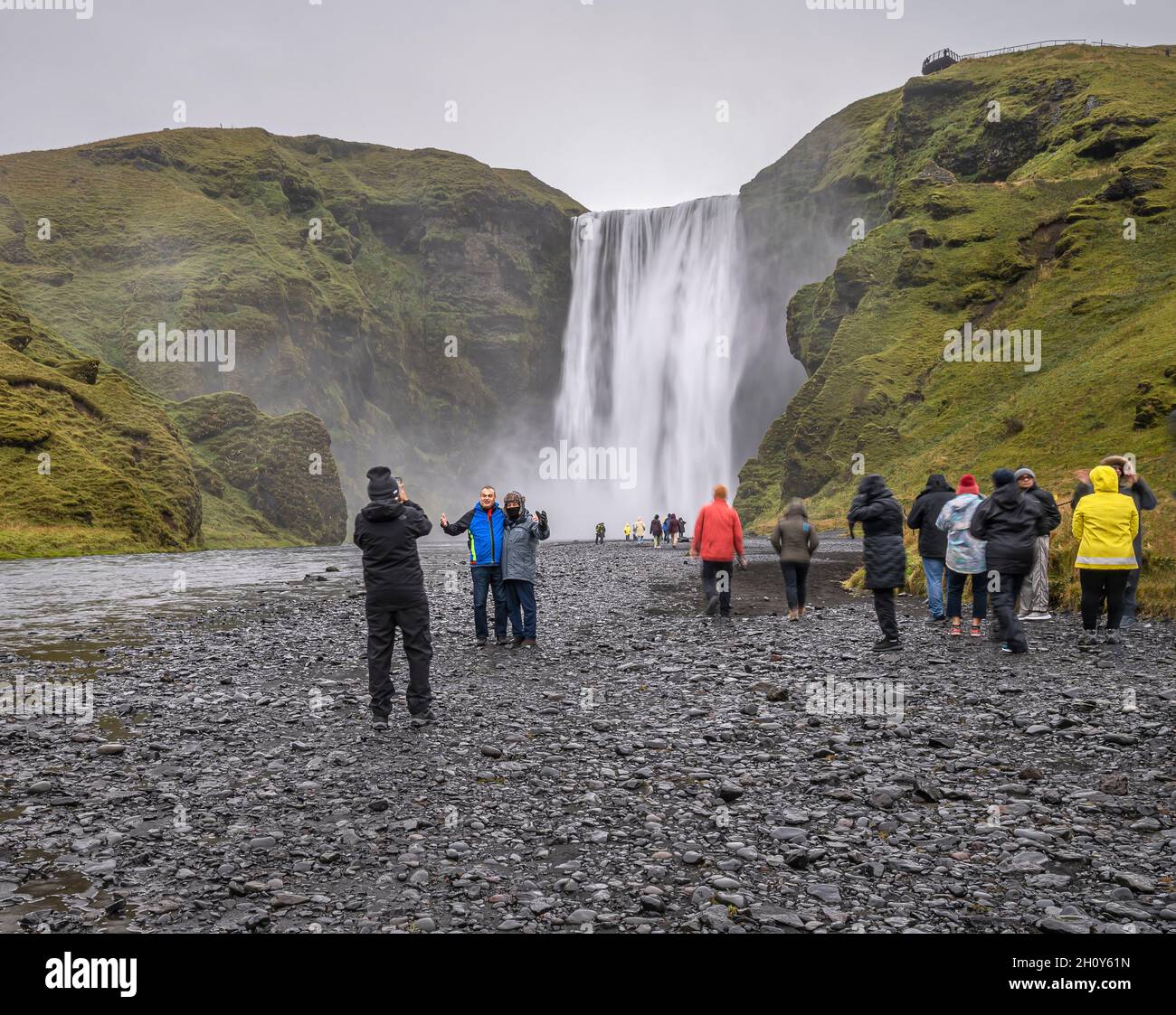 Skógar, Island – 23. September 2021: Touristen betrachten und fotografieren Skógafoss an einem regnerischen Tag Stockfoto