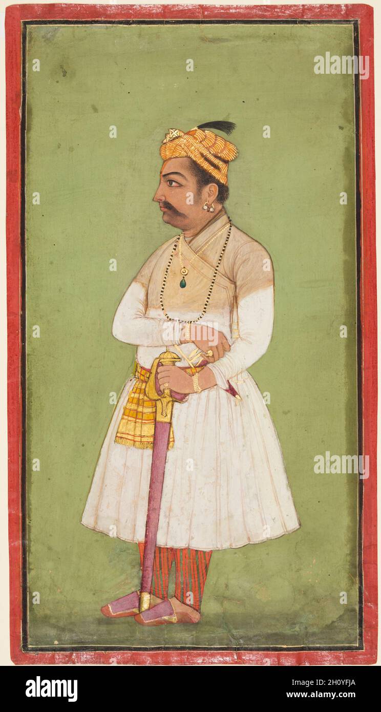 Raja Hari Sen von Mandi (r. 1604-1623-37), c. 1650. Nordindien, Himachal Pradesh, Pahari Kingdom of Mandi. Seite: 31.8 x 17.8 cm (12 1/2 x 7 Zoll); Bild: 29.8 x 15.6 cm (11 3/4 x 6 1/8 Zoll). Im Porträt ist der raja in einem Gheradar-Jama mit einer kurzen Pataka-Pataka verkleidet, ein Merkmal der Mode aus der Jahangir-Ära. Er steht selbstbewusst vor einem monochromatischen Farngrün, wobei seine linke Hand sein Schwert in einer mauvigen Scheide stützt, während seine rechte Hand auf seinen Dolch zugreift, der sicher in seinen Gürtel gesteckt ist. Stockfoto