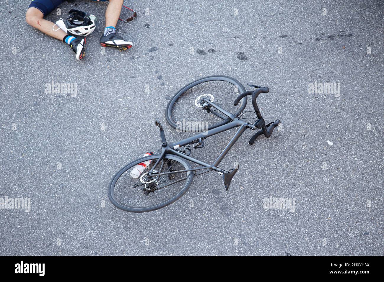 Fahrradunfall auf der Straße. Szene eines Radfahrers und eines Fahrrads auf dem Asphalt, nachdem er von einem Fahrzeug getroffen wurde Stockfoto