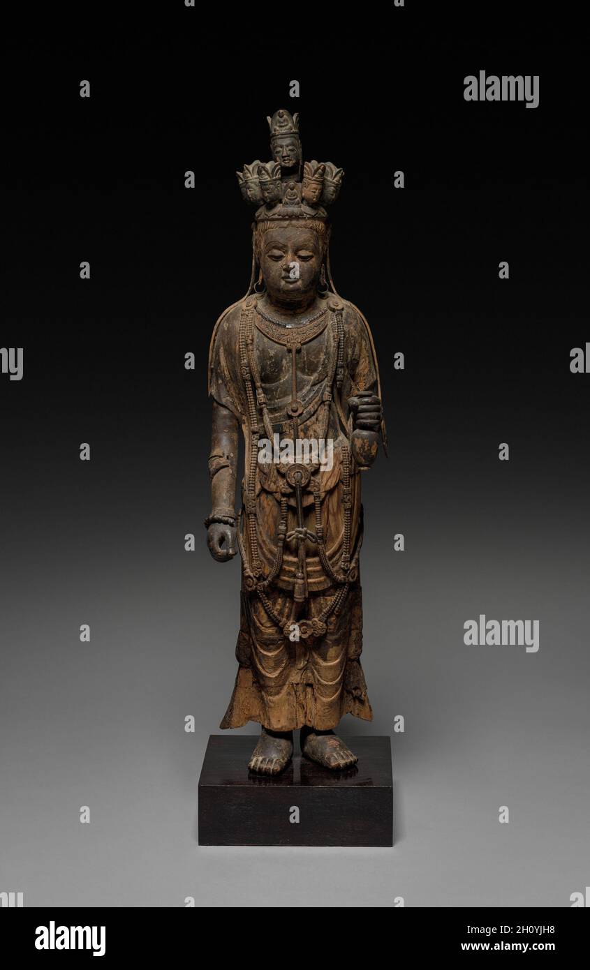 Elfköpfiger Guanyin, Ende 600. China, Tang-Dynastie (618-907). Holz; Höhe: 62.9 cm (24 3/4 in.). Guanyin, der Bodhisattva des unendlichen Mitgefühls, lässt sich an seinen Attributen erkennen: Er trägt einen winzigen Amida-Buddha in seiner Krone und hält eine Flasche mit dem Nektar des Lebens in seiner linken Hand. Insbesondere der elfköpfige Guanyin hat seine Augen und Ohren in alle Richtungen offen, um all jene zu hören, zu sehen und zu helfen, die in Not sind. Das Gewand und der Schmuck dieser anmutigen Figur erinnern uns daran, dass der historische Buddha Shakyamuni ursprünglich ein indischer Prinz war, bevor er die Erleuchtung erreichte. Auf h Stockfoto