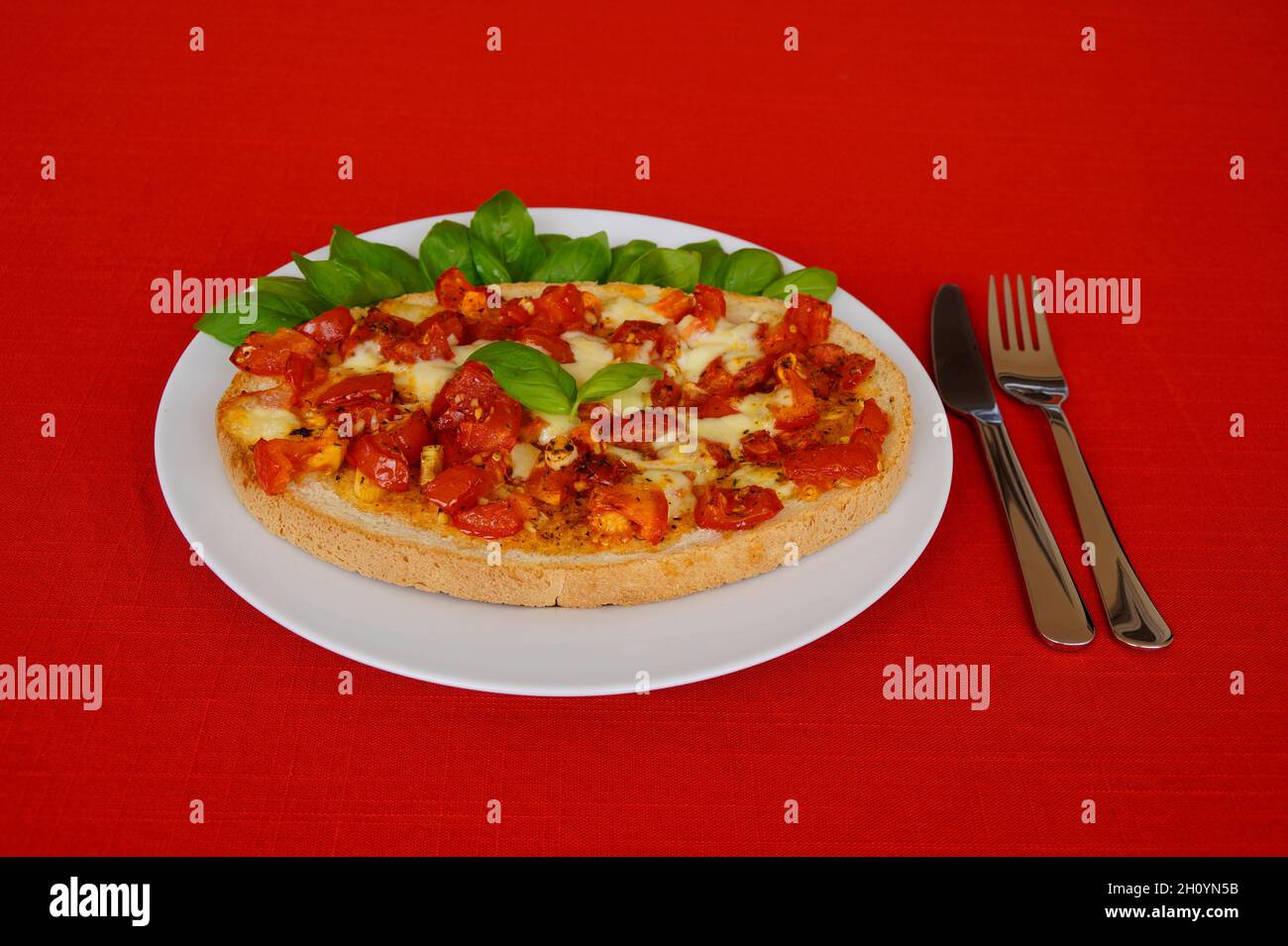 Köstliche große italienische Bruschetta mit saftigen roten Tomaten, Mozzarella, Knoblauch, Olivenöl und frischen Basilikumblättern auf einem Teller Stockfoto