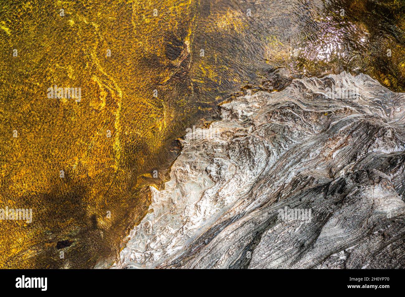 Blick von oben auf das Wasser eines Flusses und einer Felsenbank. Der Wind verleiht dem Ganzen eine hervorragende Textur. Stockfoto