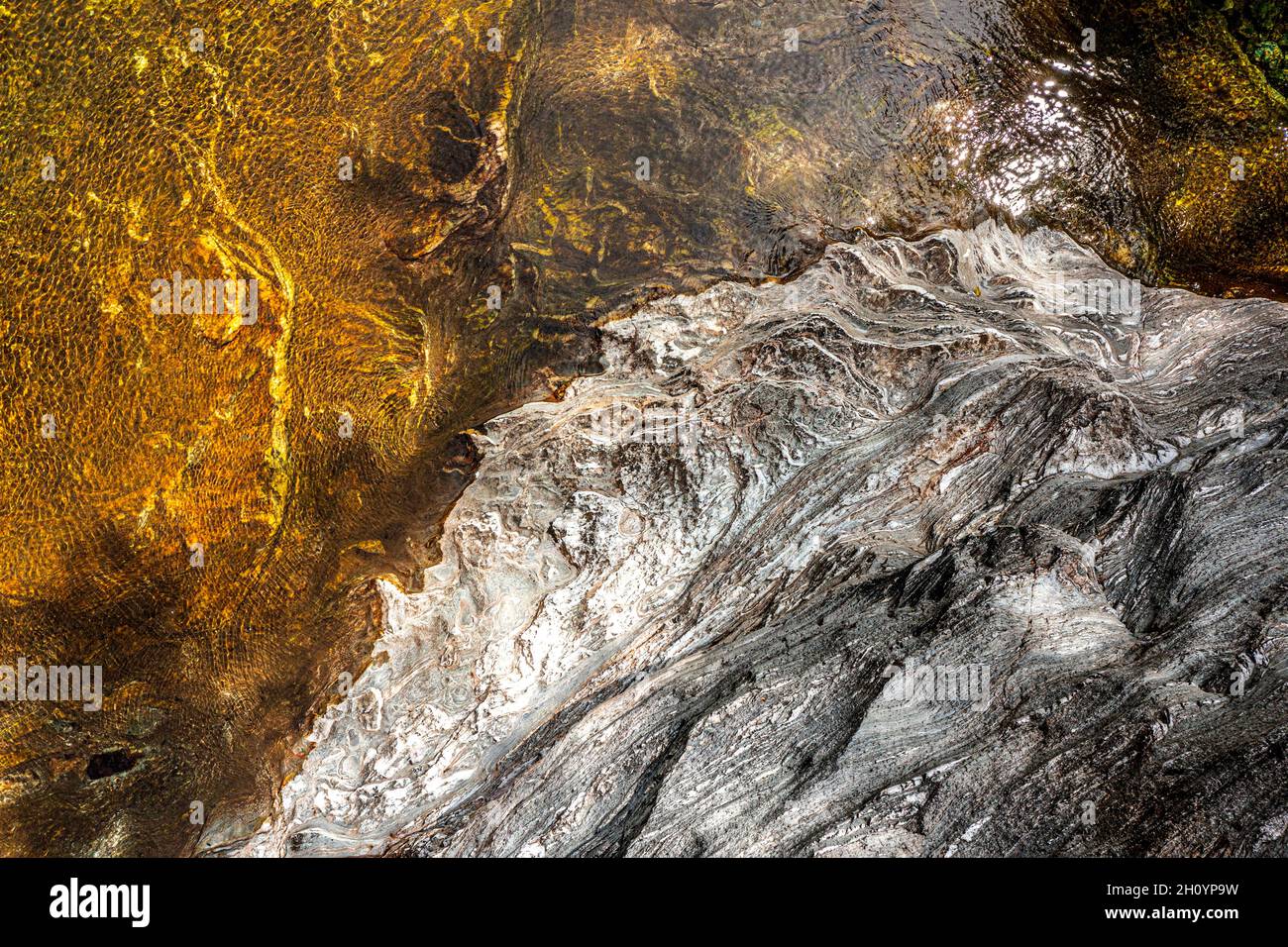 Blick von oben auf das Wasser eines Flusses und einer Felsenbank. Der Wind verleiht dem Ganzen eine hervorragende Textur. Stockfoto