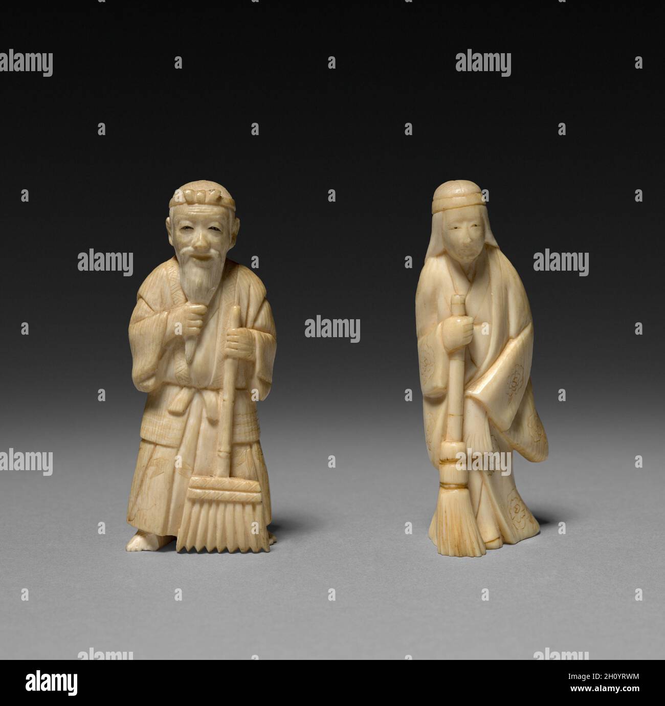 Mann mit Rake und Frau mit Besen, Anfang des 20. Jahrhunderts. Japan, Meiji-Zeit (1868-1912). Paar Elfenbeinfiguren; insgesamt: 7.8 x 2.9 cm (3 1/16 x 1 1/8 Zoll). Stockfoto