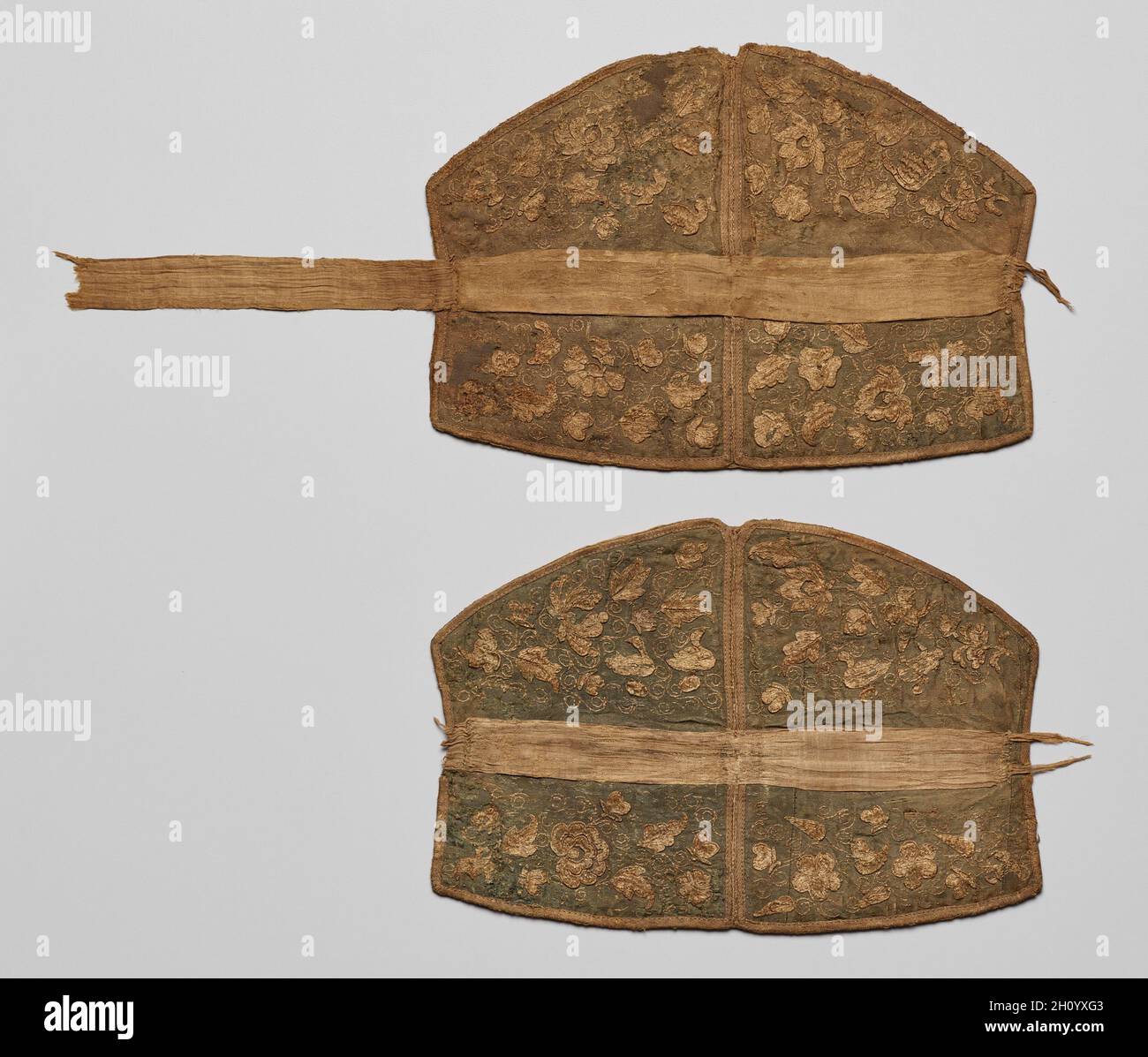 Paar Kopfstücke, 907-1125. China, Liao-Dynastie (907-1125). Stickerei, Seide; insgesamt: 22.3 x 53.8 cm (8 3/4 x 21 3/16 Zoll). Diese Kopfstücke sind bestickt mit Schmetterlingen, Vögeln, Tieren, Blumen, Blättern, Und zarte Weinrollen. Im Allgemeinen ist das Design mit dem Thema des Lotusteich, am besten bekannt aus Liao Grabmalereien verbunden. Paarige Enten oder Gänse, die im Wasser schwimmen und in entgegengesetzte Richtungen schauen, scheinen im Norden Chinas populär geworden zu sein, bevor sie sich weiter nach Süden und nach Zentralasien ausbreiteten. Auf der anderen Seite sind Liegeradtiere, die zurückblicken, ein zentralasiatisches Bild, das Stockfoto