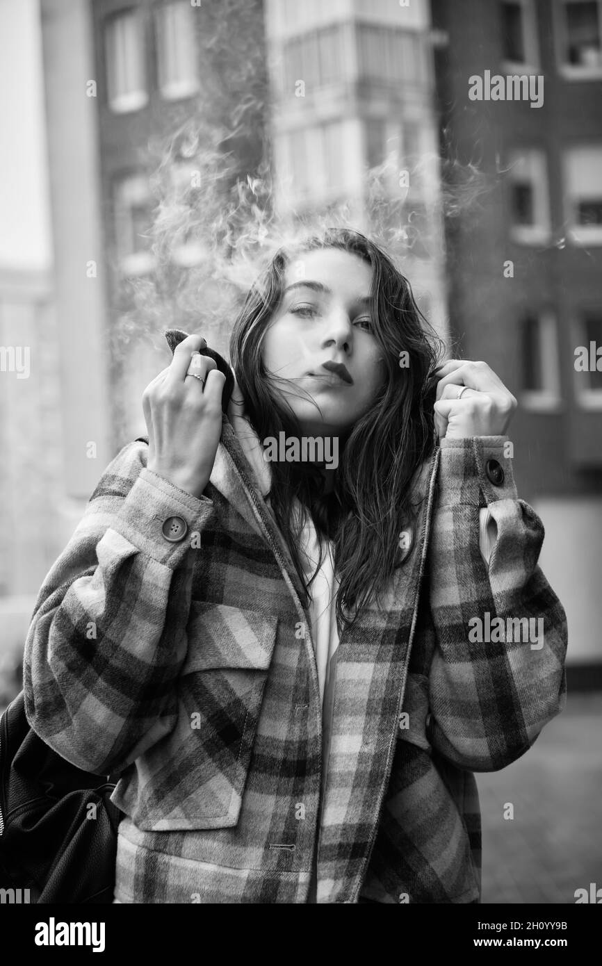 Junge Frau auf der Stadtstraße atmen Rauch Nahaufnahme Porträt, monochrom Stockfoto
