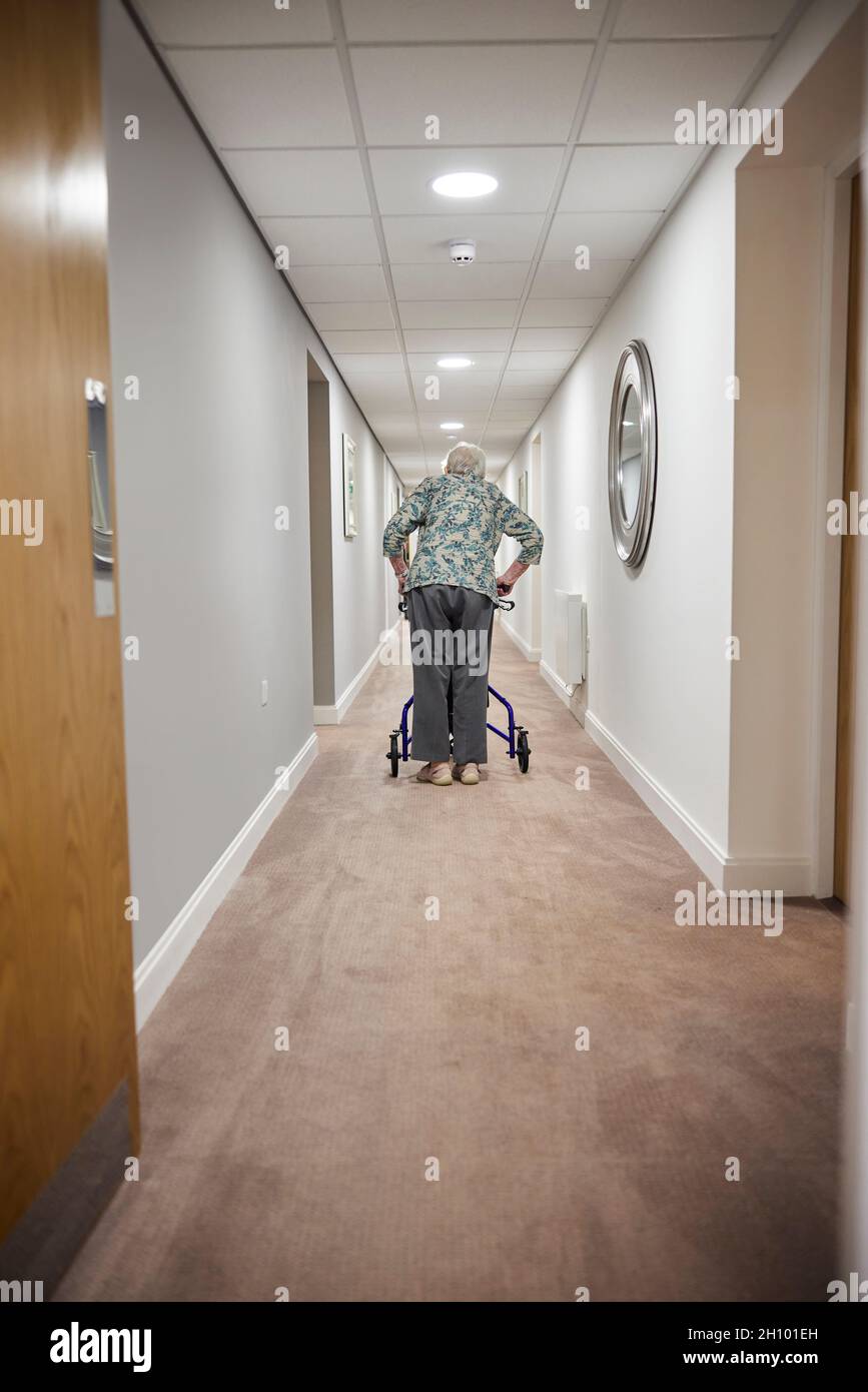 Rückansicht Einer Älteren Frau Mit Walker, Die Im Altersheim Den Korridor Entlang Läuft Stockfoto