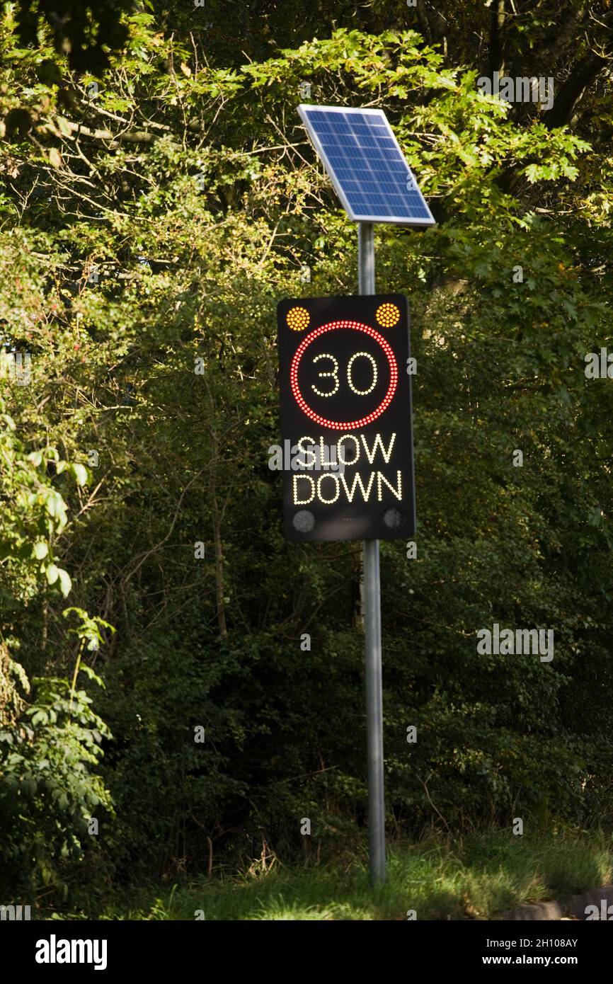 30 mph Slow Down Zeichen in Großbritannien. Aufnahme vor einem Hintergrund aus Laub Stockfoto