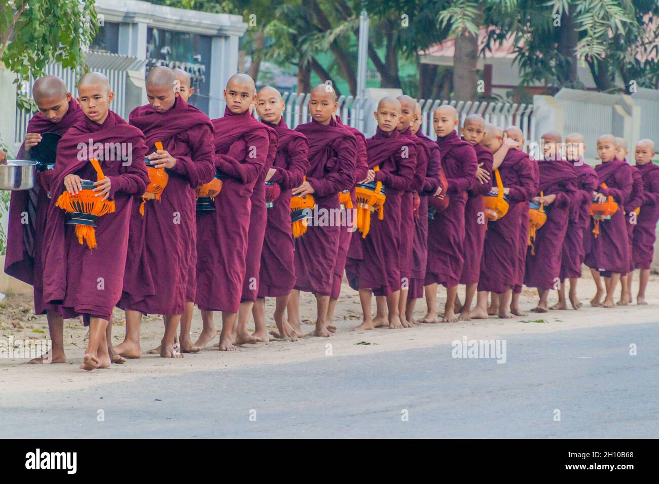 BAGAN, MYANMAR - 8. DEZEMBER 2016: Reihen buddhistischer Mönche mit Schalen, die ihre täglichen Almosen sammeln. Stockfoto