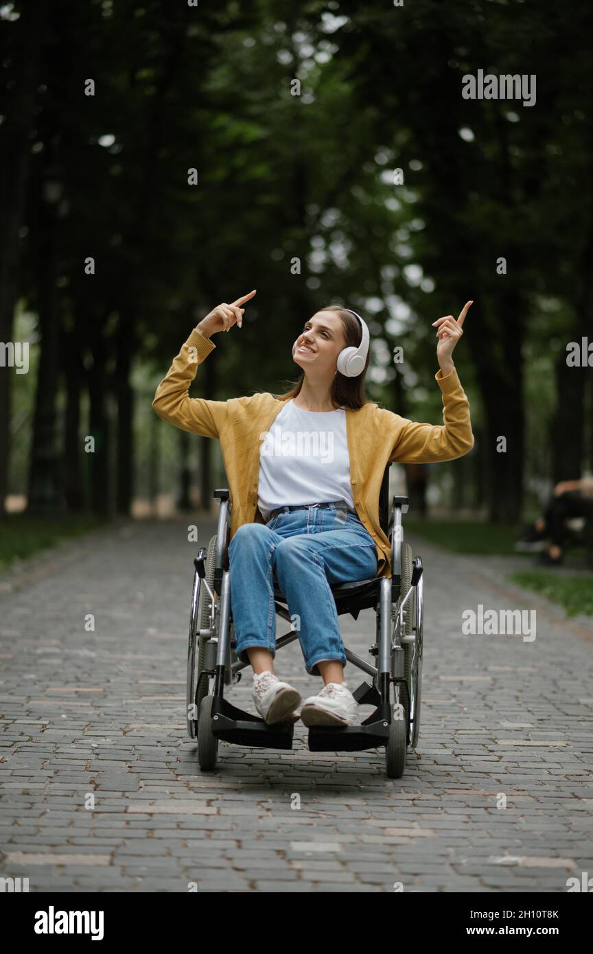 Behinderte Frau im Rollstuhl hört Musik Stockfoto