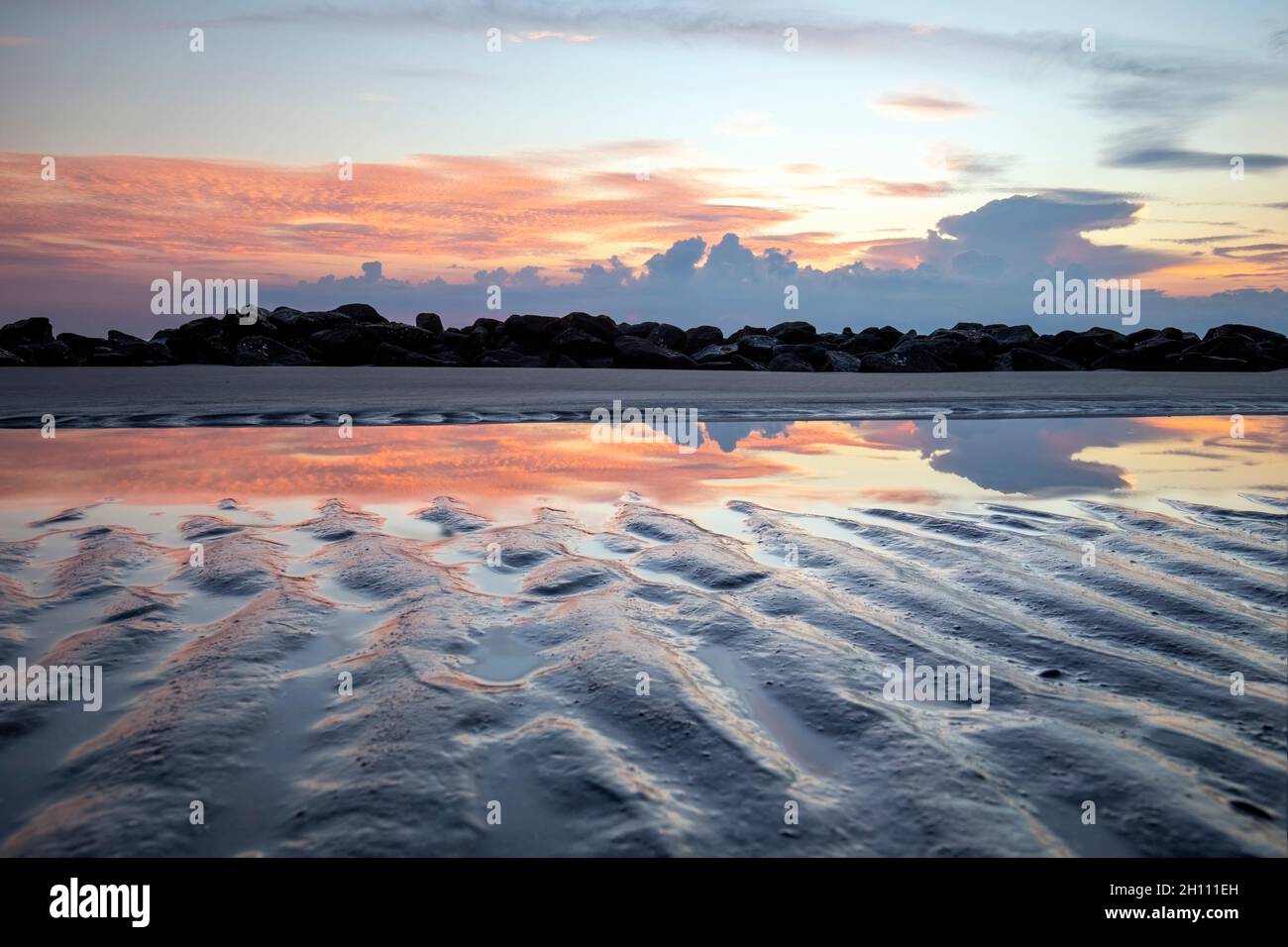 Sandmuster und Reflexionen eines Gezeitenpools bei Sonnenaufgang - Driftwood Beach - Jekyll Island, Georgia, USA Stockfoto