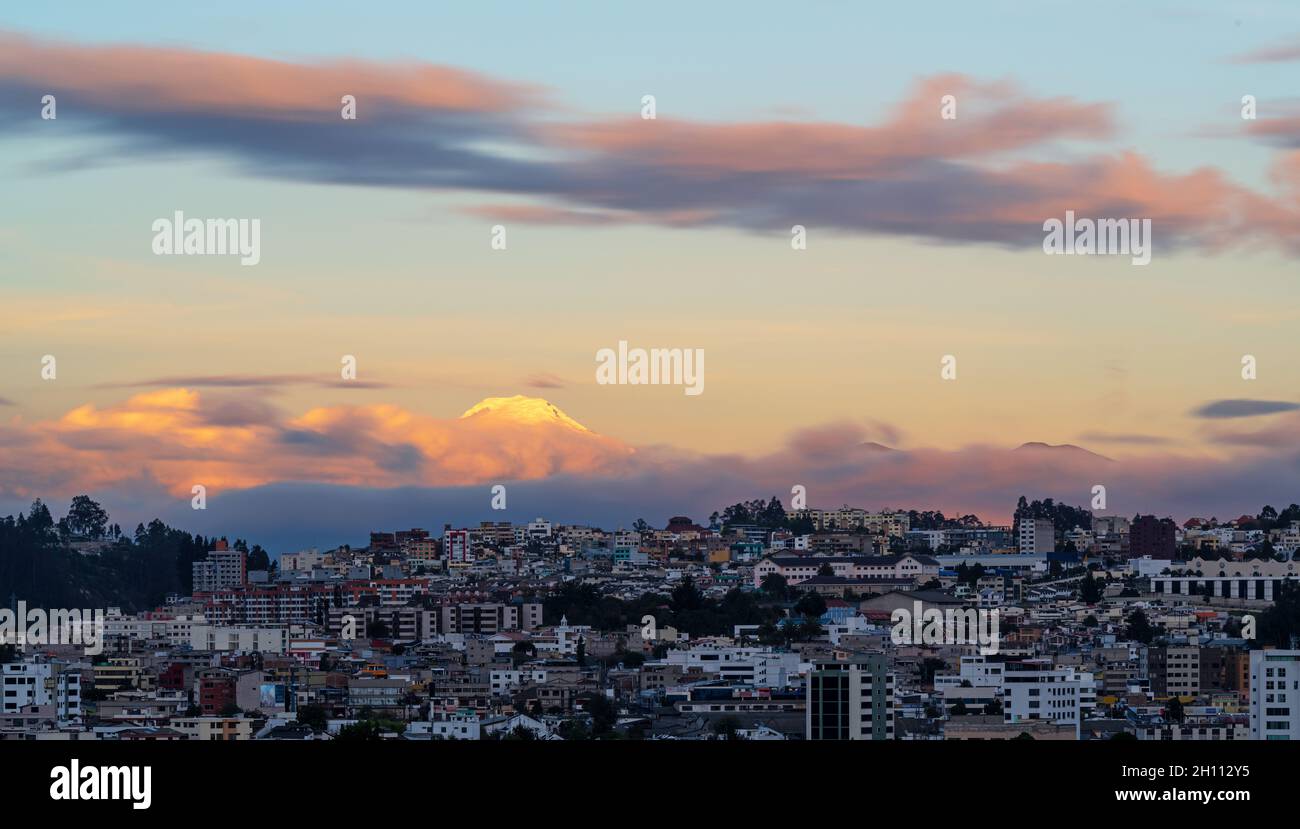 Stadtbild von Quito bei Sonnenuntergang mit Vulkan Cayambe, Ecuador. Stockfoto